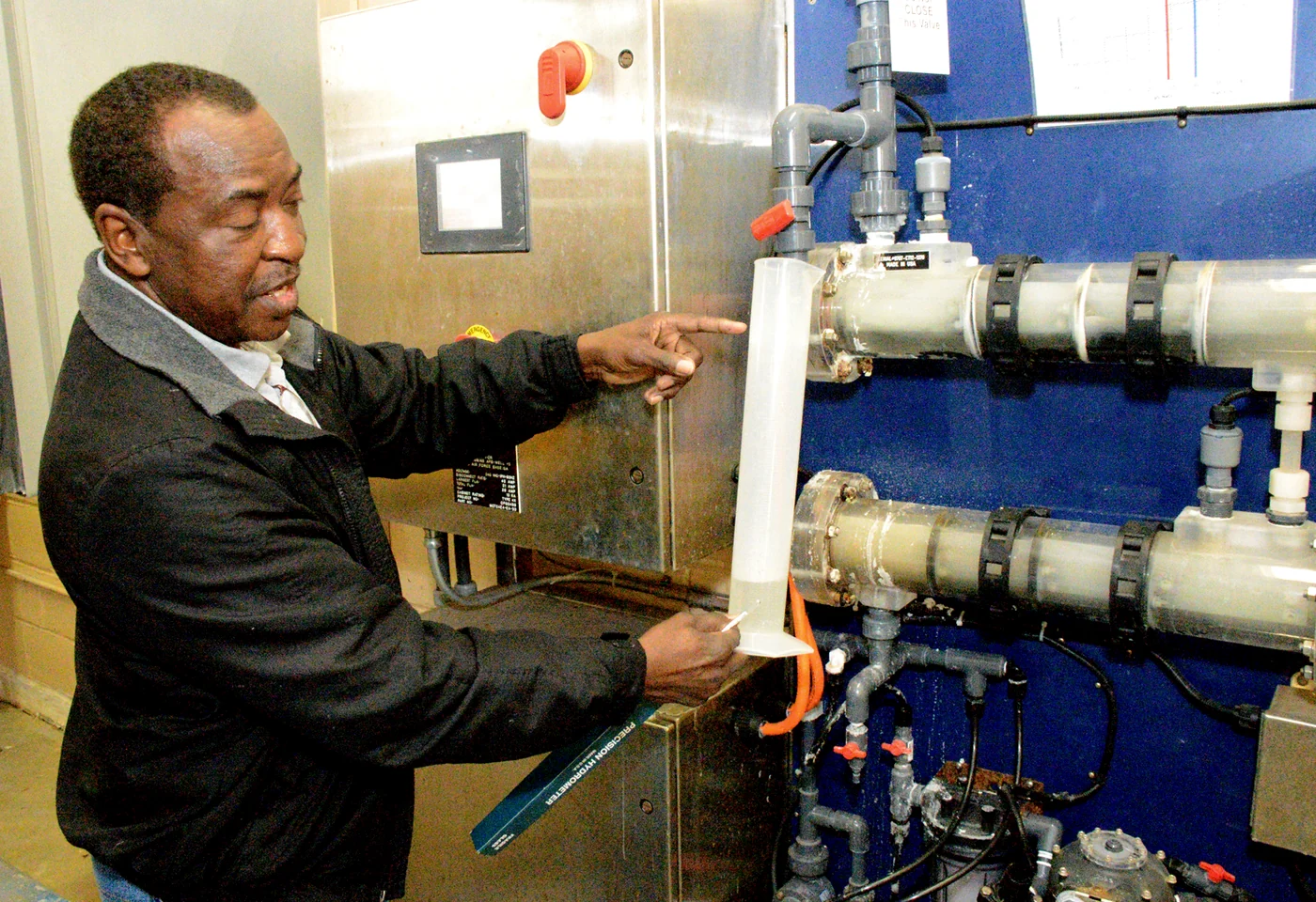 A certified water treatment plant operator explaining a chlorine generation system inside a water facility